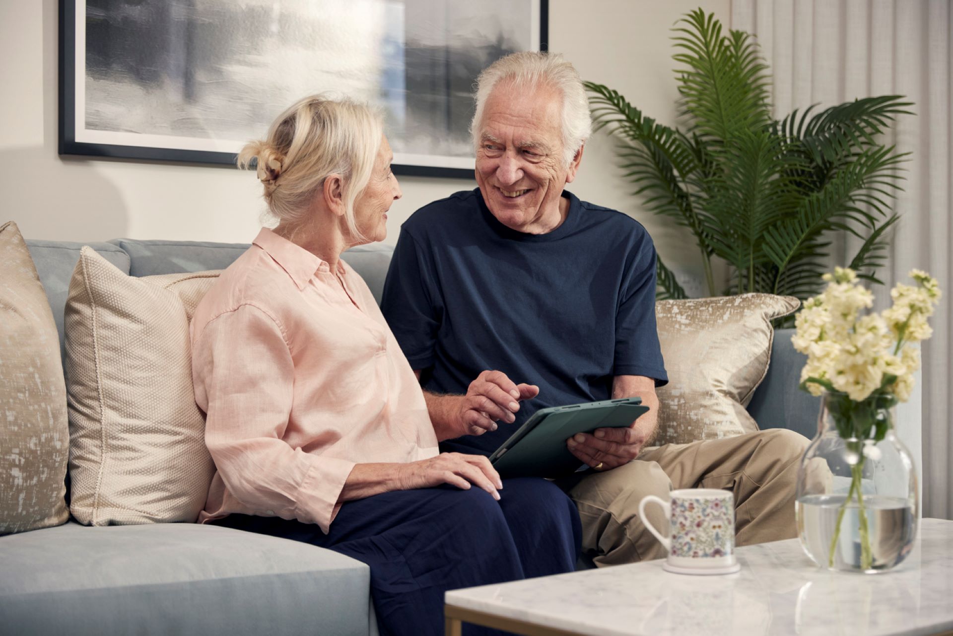 An elderly couple sitting on the sofa in a new build apartment.