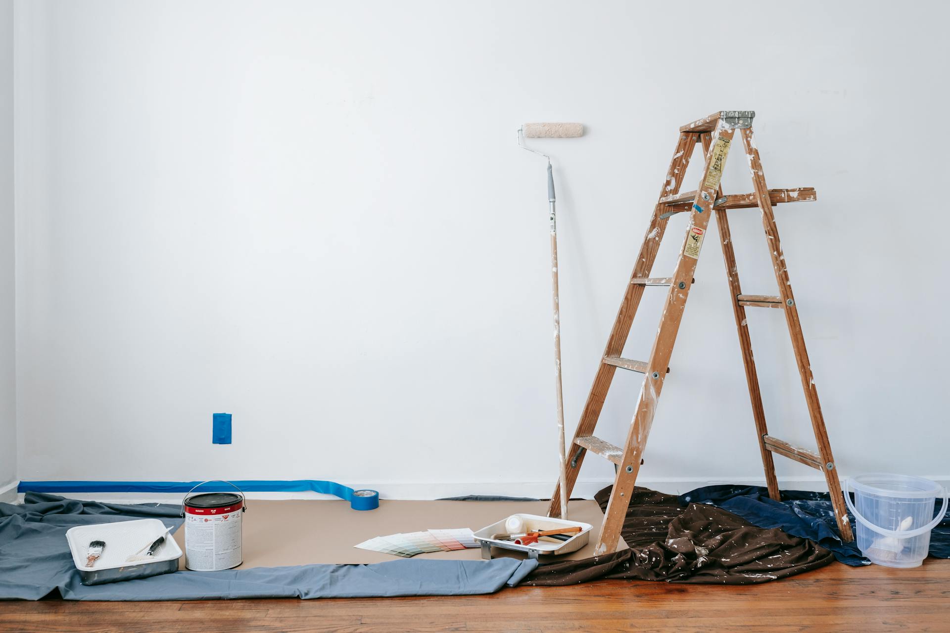 A home under renovation with a ladder, pain roller and paints.