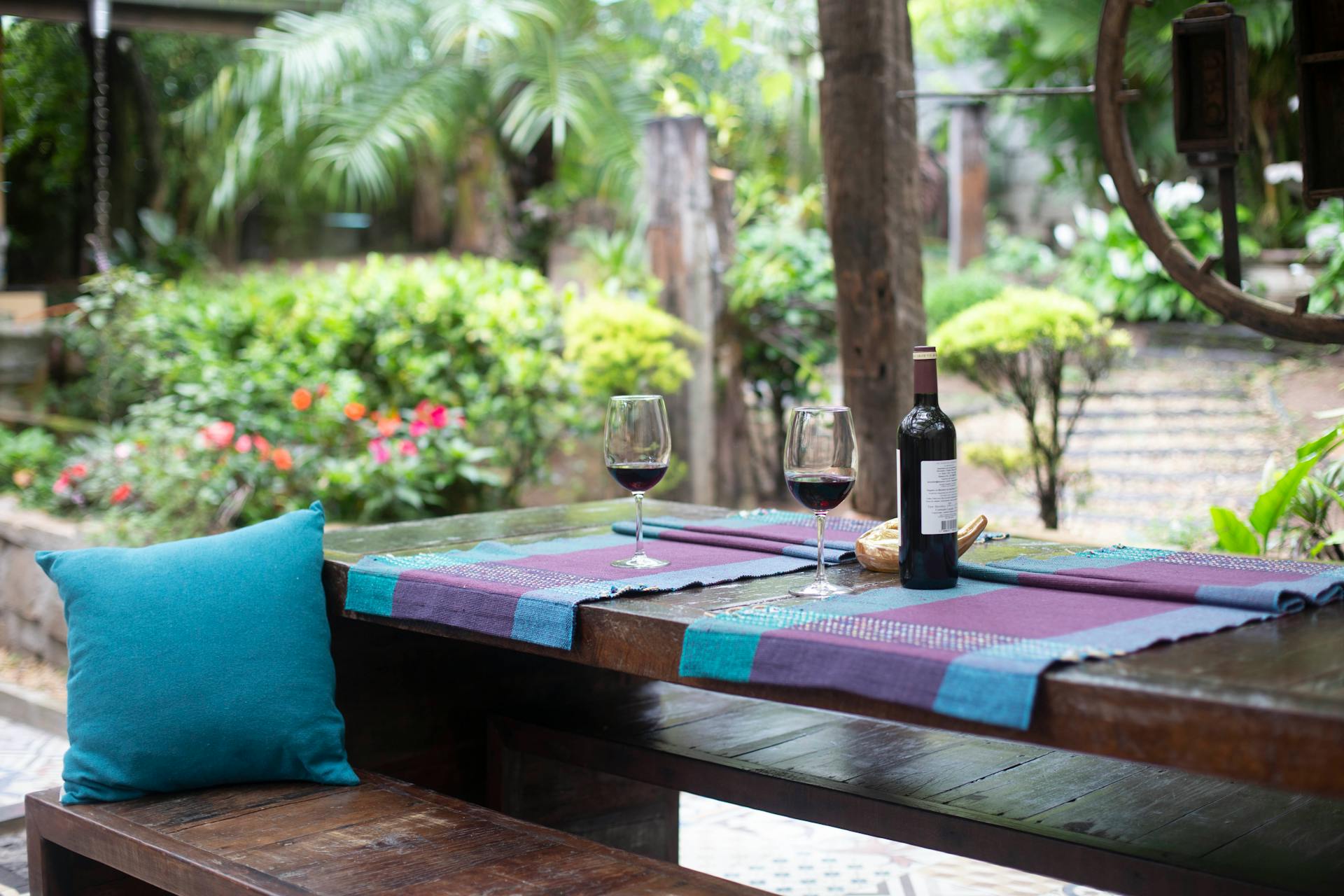 A garden dining table with purple mats and wine on it.