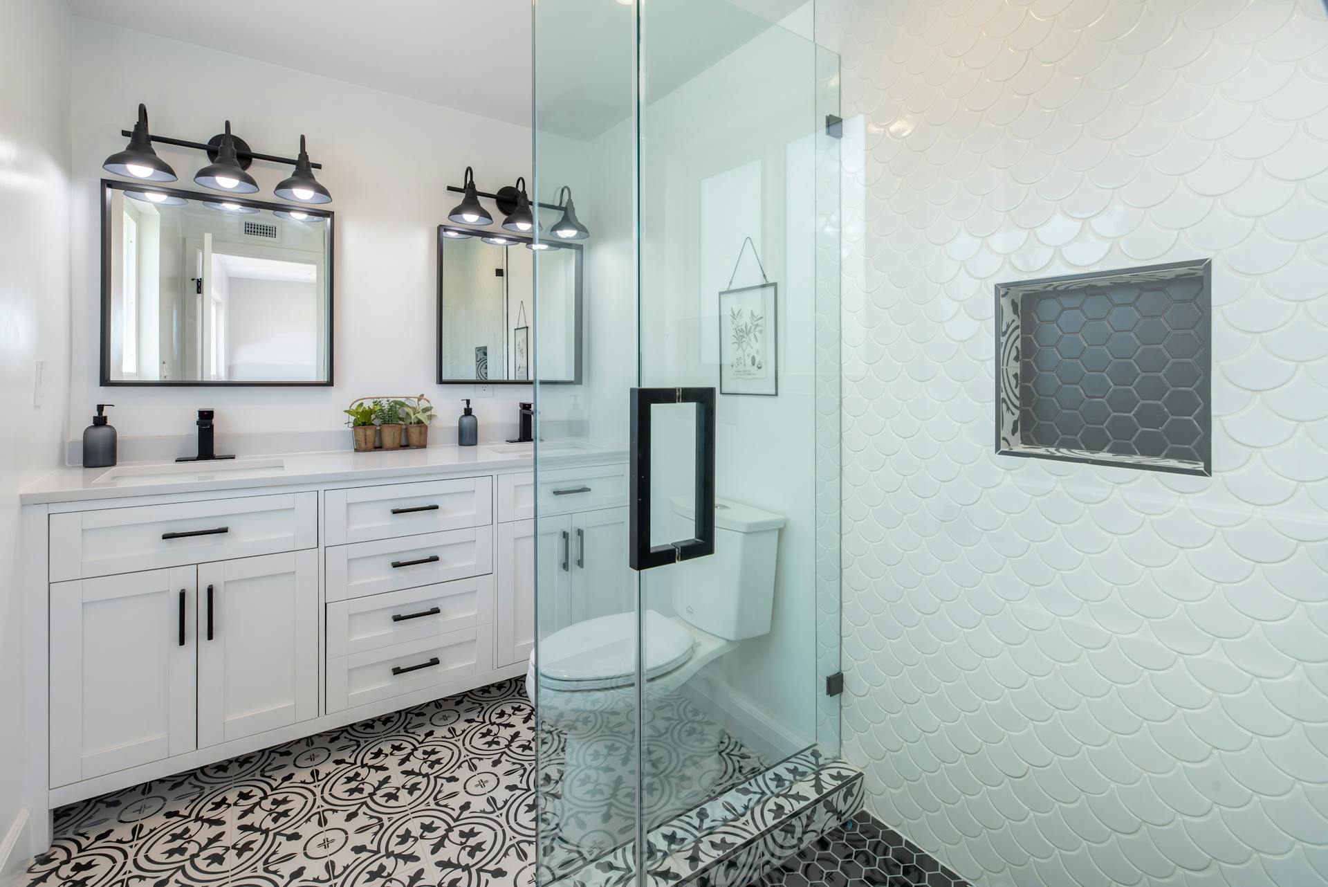 A modern bathroom with walk-in shower and double sink with mirrors.