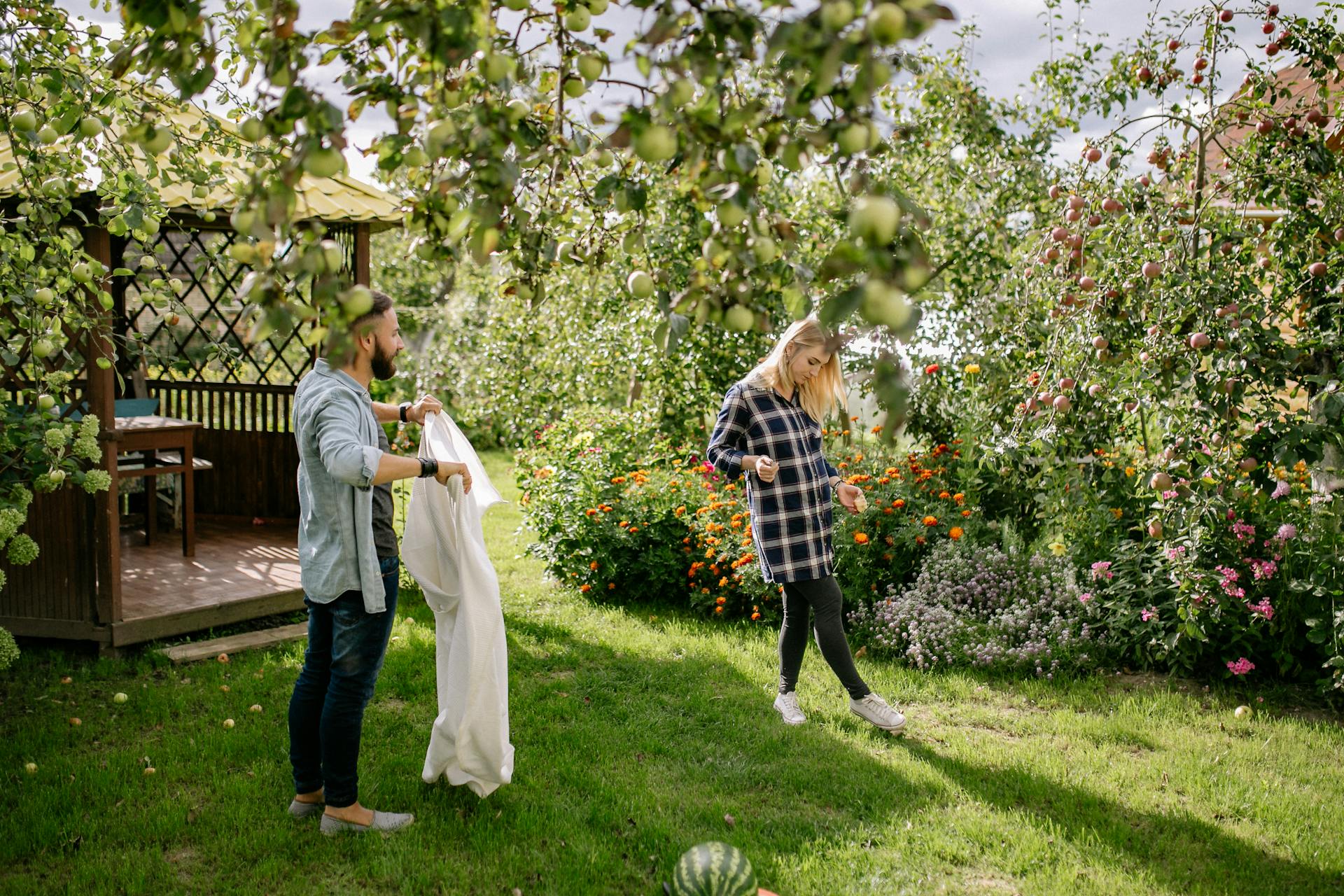 A couple in their garden, in front of a wooden garden gazebo.