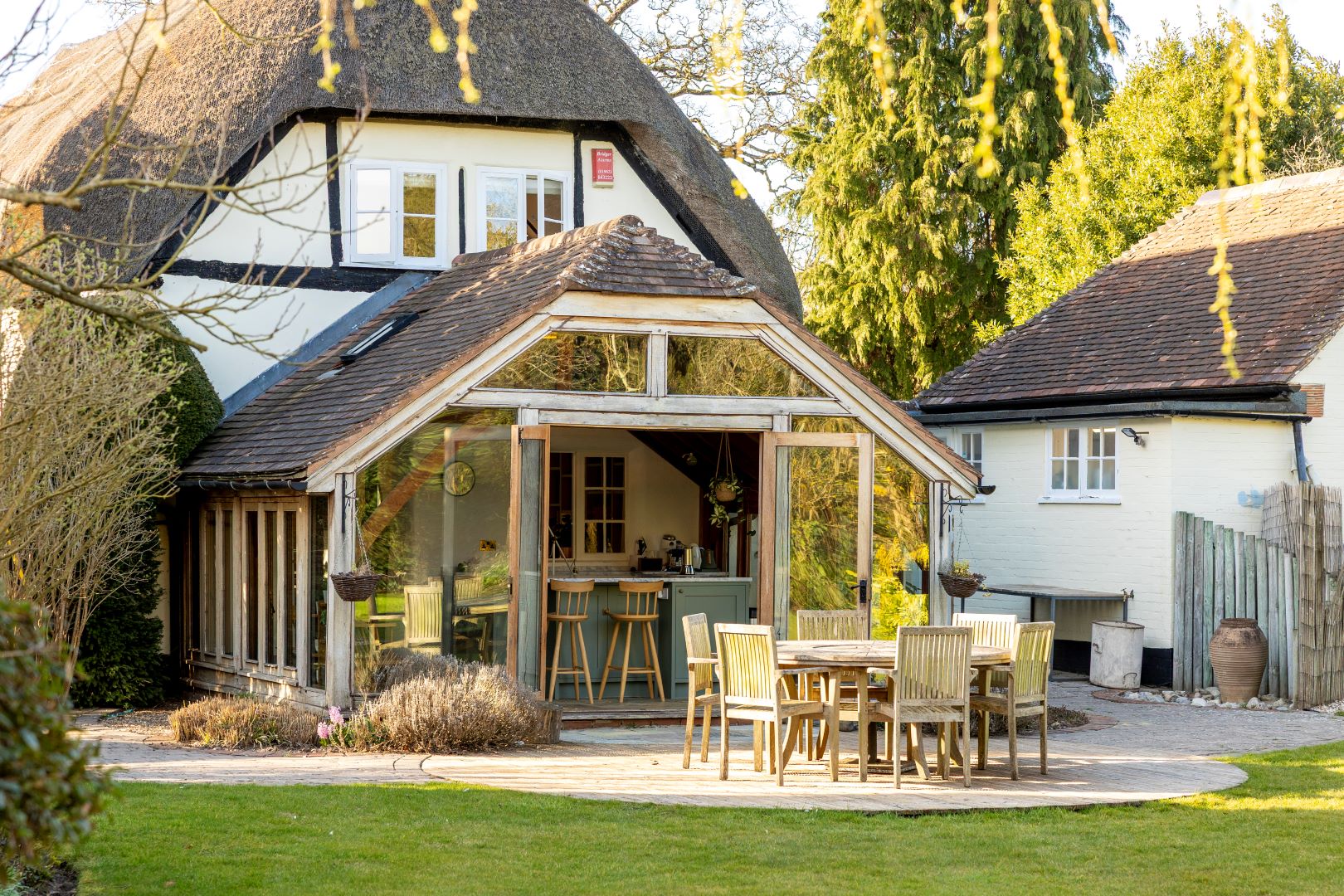 Thatched cottage with summer kitchen leading on to patio with outdoor dining table and chairs
