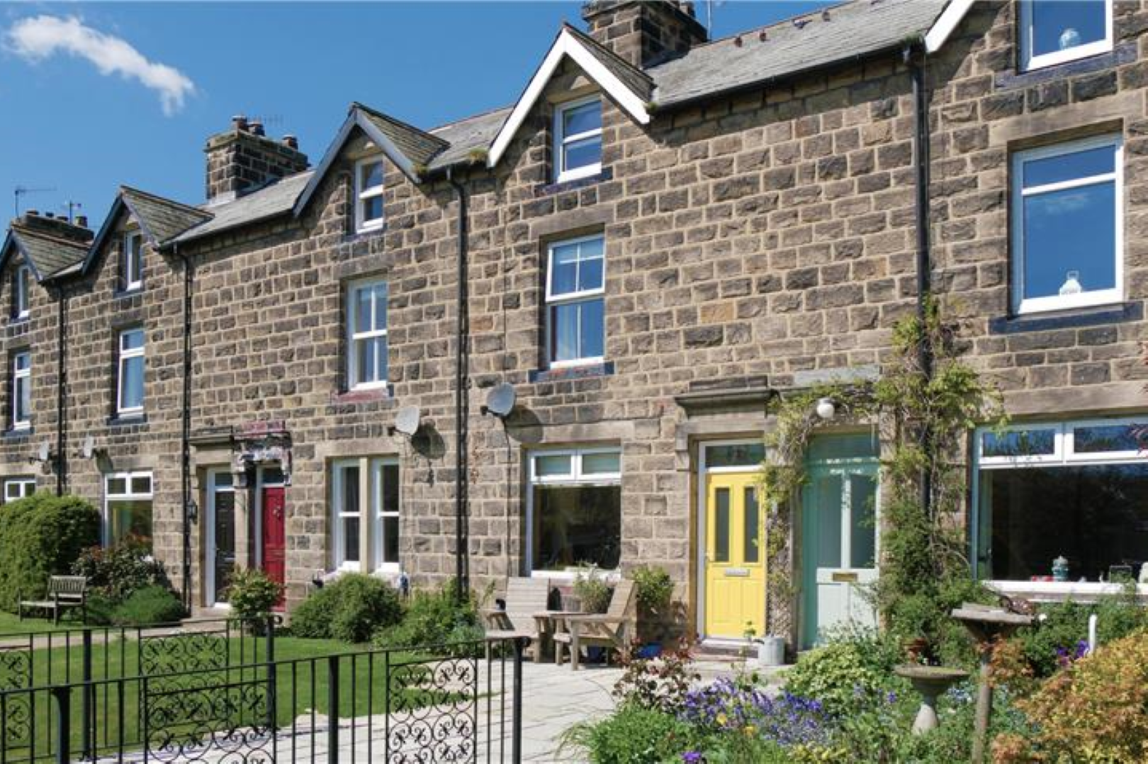 Row of stone terraced houses with different coloured doors.