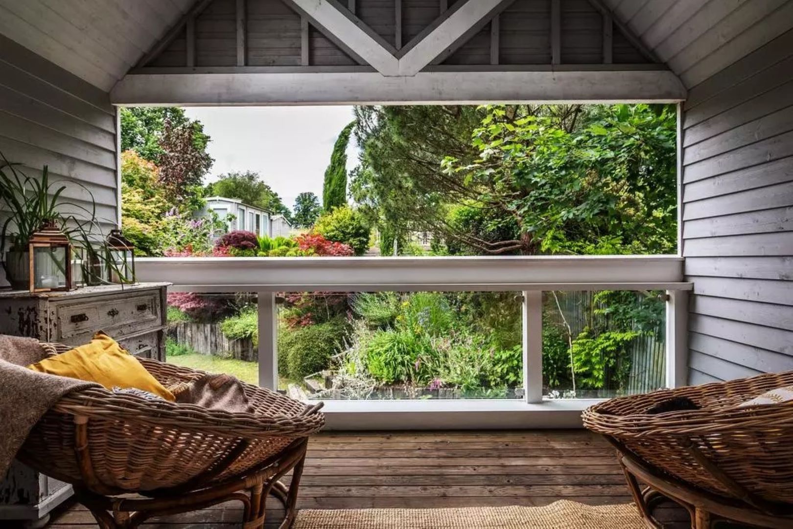 Two chairs sitting on a balcony looking out over green plants 