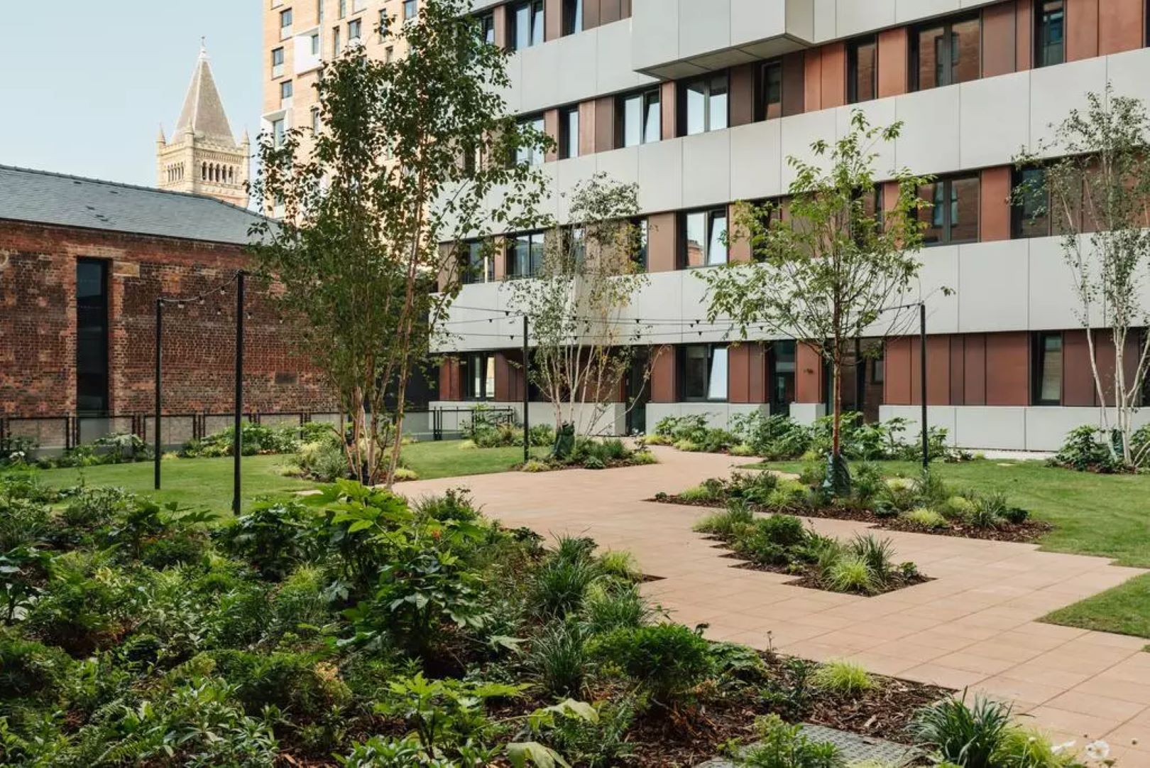 City garden with flower and shrub beds in between buildings