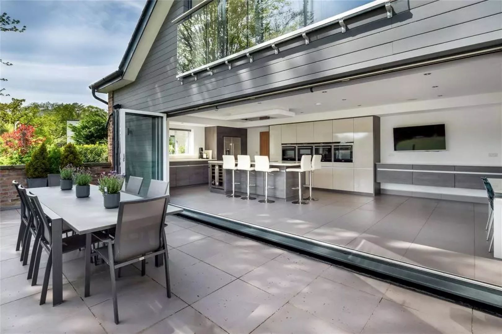 Kitchen with island counter and bifold doors leading out onto a terrace with outdoor dining table