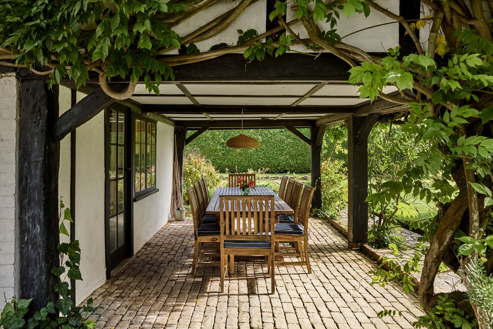 An outdoor dining area with vines growing up and around wooden beams. 