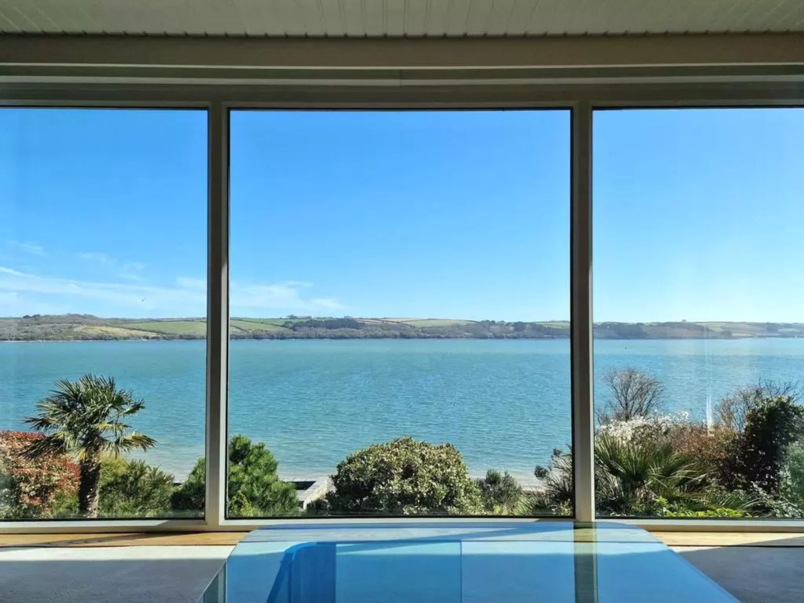 A set of three windows in a row, looking out towards the sea and land in the background.
