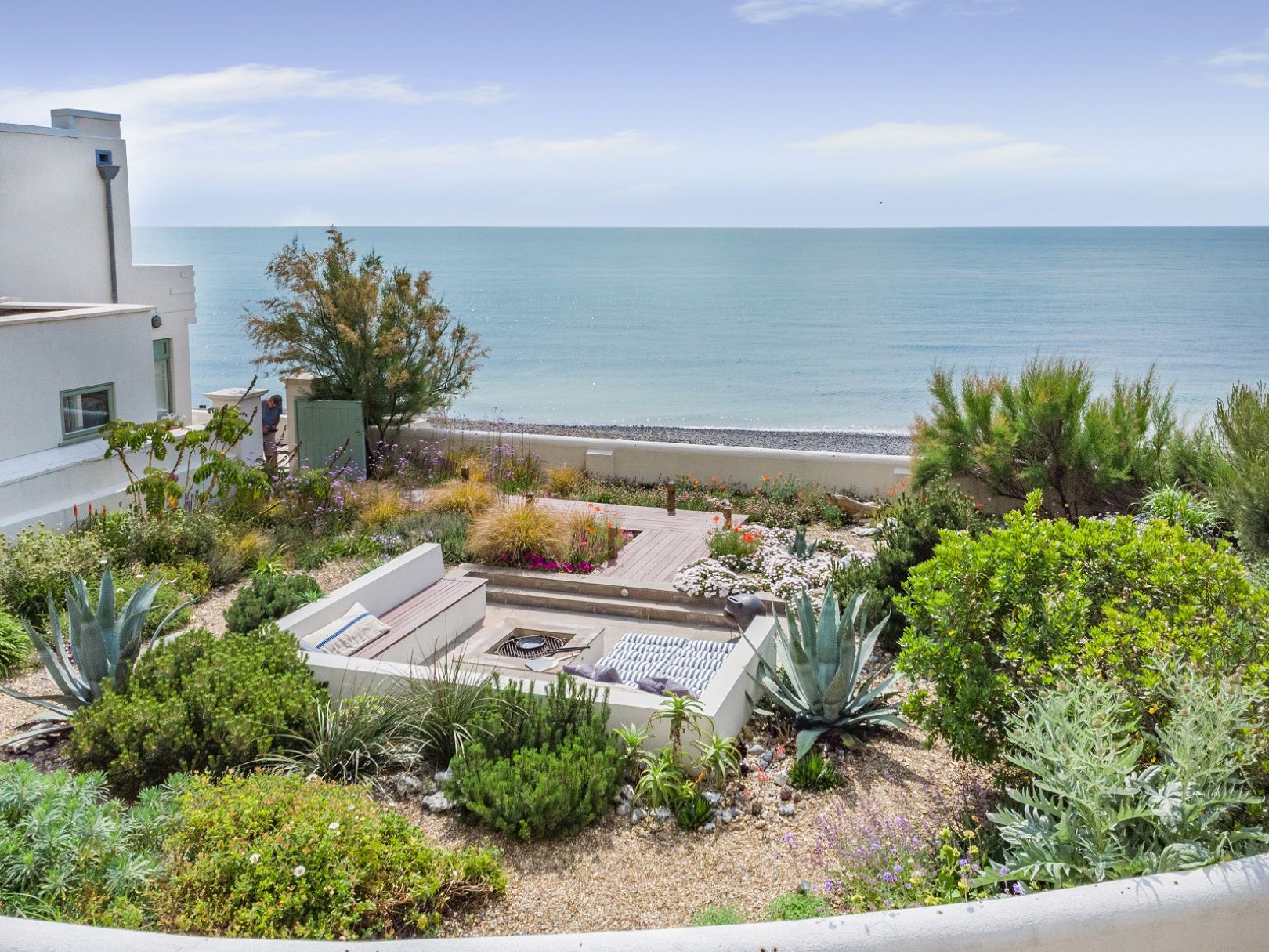 A Mediterranean garden with white, square, sunken seating area, looking out to sea. 