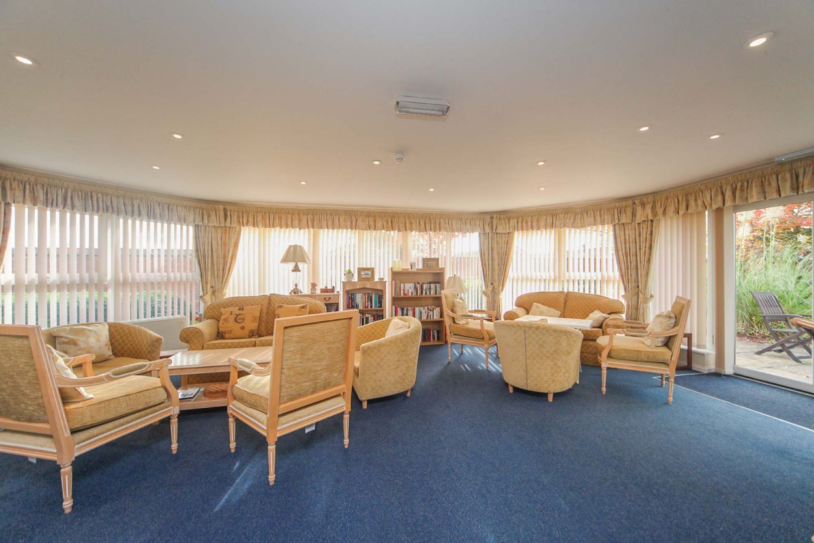 A retirement home living room with cream furniture and blue carpets