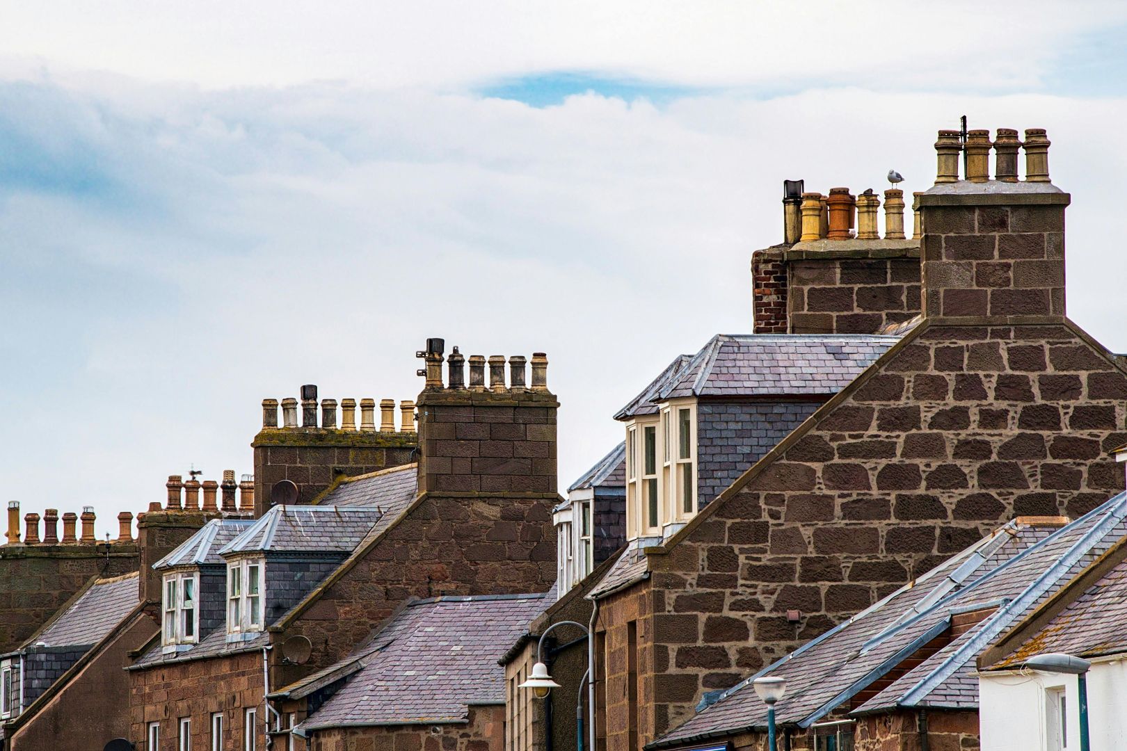 Row of rooftops with brick chimneys and slate tiles