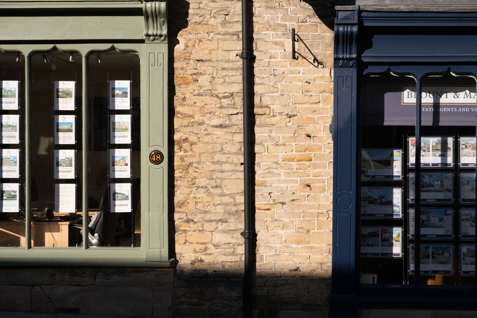 Two shop windows with different estate agent listings in them.