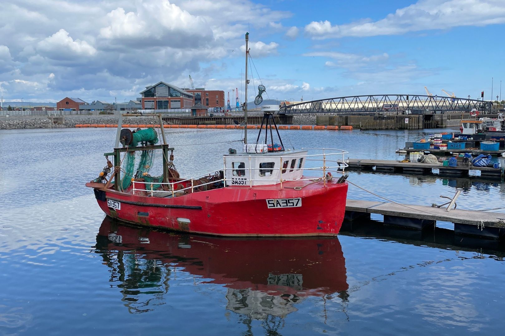 A fishing boat with red hull sitting in a marina